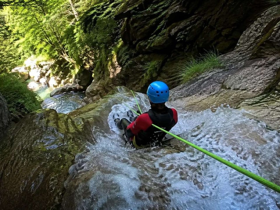 Barranquista con casco y neopreno descendiendo un tobogán de agua controlado
